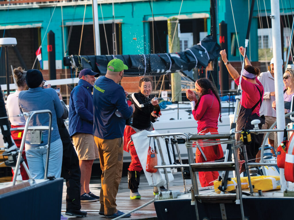 Woman popping champagne celebrating historic sailing feat