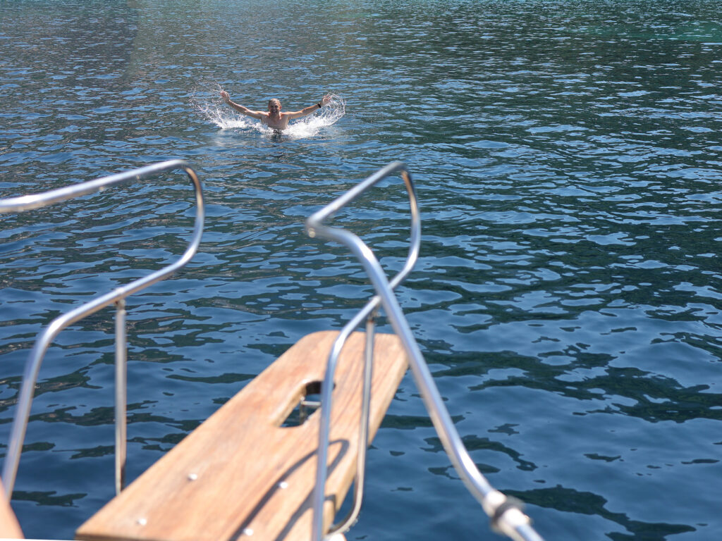 man is swimming in the open sea, jumped from the bow of a yacht