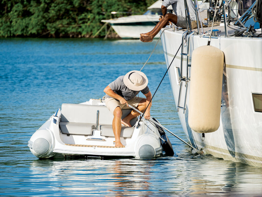 Male deckhand with a hat washing a sailing superyacht at dock in