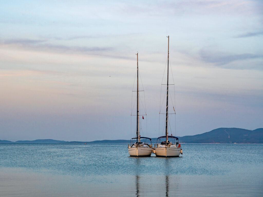 Two sailingboats moored and attached together in sunset.